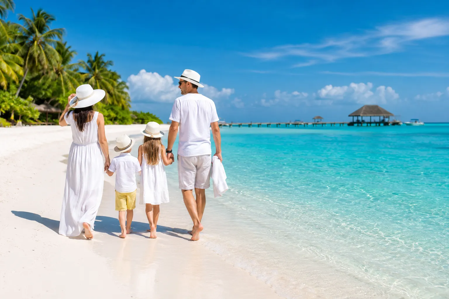 Family walking on a white sand beach at a luxury resort